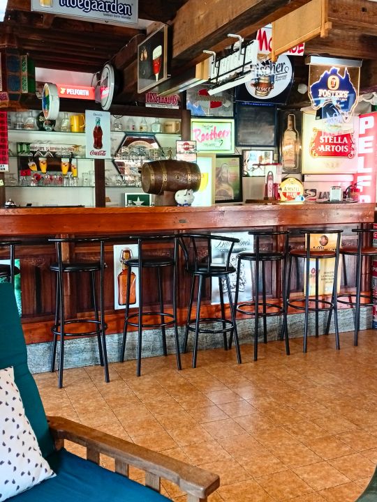 L'Estaminet — Un véritable bar d'époque de près de 5 mètres de long, avec sa verrerie, ses enseignes lumineuses rétro et ses anciennes banquettes. Un espace convivial pour les pauses, les échanges et les moments qui se prolongent. L'Estaminet — Un véritable bar d'époque de près de 5 mètres de long, avec sa verrerie, ses enseignes lumineuses rétro et ses anciennes banquettes. Un espace convivial pour les pauses, les échanges et les moments qui se prolongent.